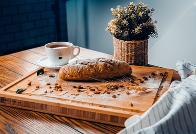 咖啡杯旁的烤面包都放在棕色木板上